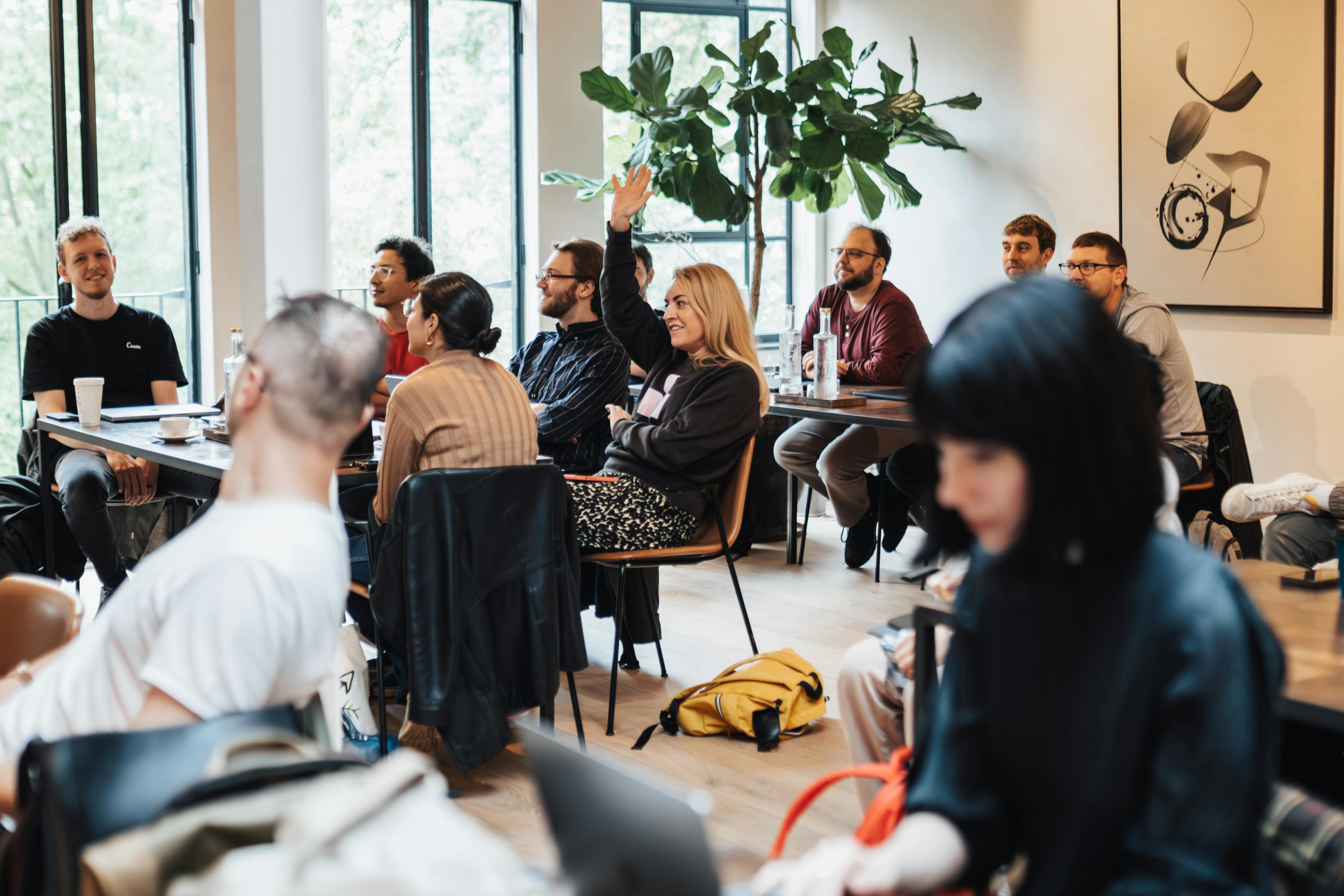 Members of a Pods Offline classroom lecture pod listening to a guest speaker in a sunlit London room, real people learning together at a small recurring weekly class through Pods Offline