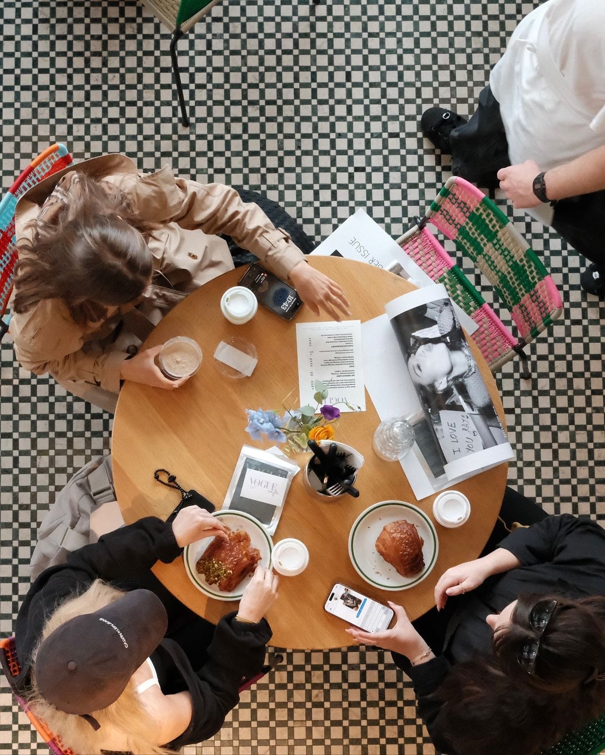 Two pairs of friends meeting at a small café through a Pods Offline coffee meetup, phones down, croissants, slow morning conversation between strangers turning into a recurring weekly hang